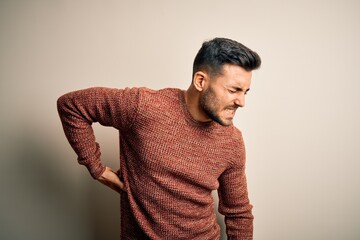 Young handsome man wearing casual sweater standing over isolated white background Suffering of backache, touching back with hand, muscular pain