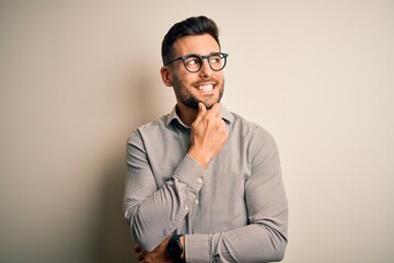 Young handsome man wearing elegant shirt and glasses over isolated white background with hand on...