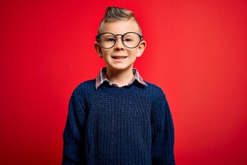 Young little caucasian kid with blue eyes standing wearing smart glasses over red background with a happy and cool smile on face. Lucky person.