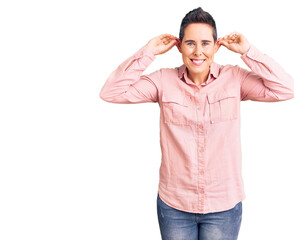 Young woman with short hair wearing casual clothes smiling pulling ears with fingers, funny gesture. audition problem