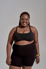 Be comfortable. Plump, plus size african american woman in black sportswear laughing while standing...