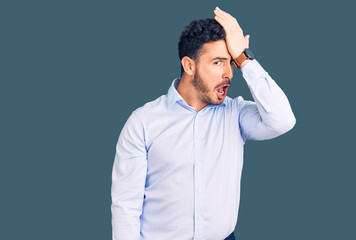 Young hispanic man wearing business clothes surprised with hand on head for mistake, remember...