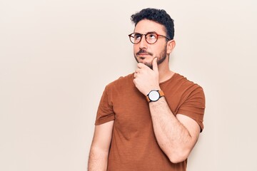 Young hispanic man wearing casual clothes thinking concentrated about doubt with finger on chin and looking up wondering