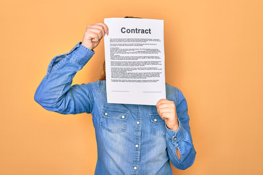 Woman holding contract document paper standing over isolated yellow background