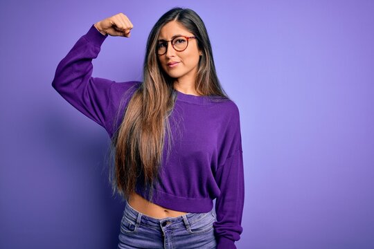 Young beautiful smart woman wearing glasses over purple isolated background Strong person showing arm muscle, confident and proud of power
