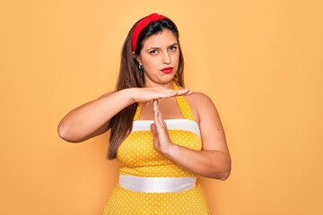 Young hispanic pin up woman wearing fashion sexy 50s style over yellow background Doing time out...