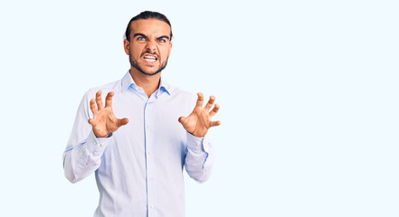 Young handsome man wearing business clothes smiling funny doing claw gesture as cat, aggressive and sexy expression