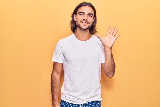Young handsome man wearing casual clothes showing and pointing up with fingers number five while smiling confident and happy.