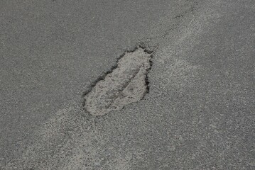 one big pothole on the gray asphalt road