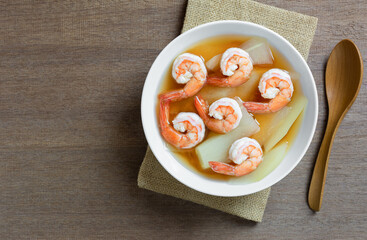 top view of hot and sour soup with shrimp and green papaya in a ceramic bowl on wooden table. asian homemade style food concept.