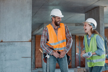 Two happy civil engineer and maintenance engineer in protective vests and helmets working on a...