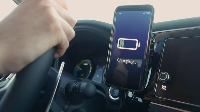 Smartphone Connected to a car charging its battery while driving the vehicle.
