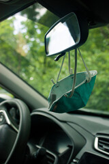 A creative solution during the ongoing COVID-19 pandemics: A medical face mask is attached to the rear view window of a car for convenient access to reuse as needed. 