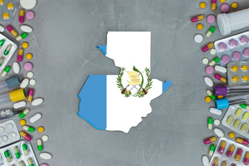 The Guatemala State began research for treatment and medicine to combat the pandemic outbreak disease coronavirus. Medicine, pills, needles, syringes and Guatemala map and flag on gray background.