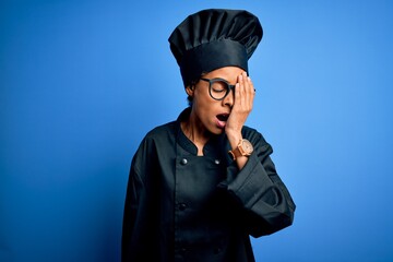 Young african american chef woman wearing cooker uniform and hat over blue background Yawning tired covering half face, eye and mouth with hand. Face hurts in pain.