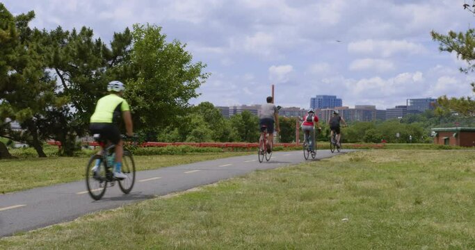 Cyclists on Gravelly Point Bike Path ride to Ronald Reagan Airport DCA, warm sunny day, blue sky, Crystal City in Background