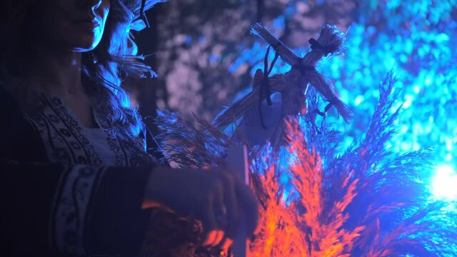 A forest witch brews a potion holding a Voodoo doll