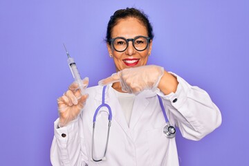 Middle age senior professional doctor woman holding syringe with medical vaccine very happy pointing with hand and finger