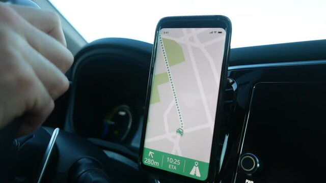 The driver of a vehicle using the GPS of his smartphone to navigate in his car. Closeup on the mobile device being used.
