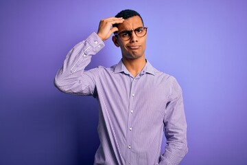 Obraz premium Handsome african american man wearing striped shirt and glasses over purple background worried and stressed about a problem with hand on forehead, nervous and anxious for crisis