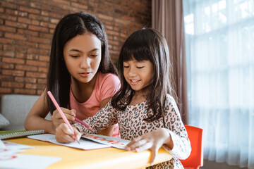 sister help her little sibling to learn and study homework while staying home