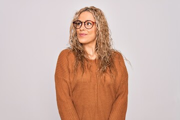 Young beautiful blonde woman wearing casual sweater and glasses over white background smiling looking to the side and staring away thinking.