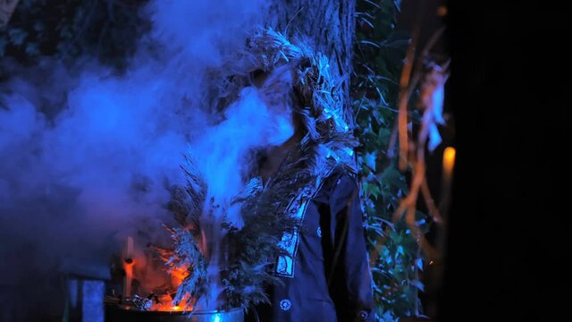 A forest witch brews a potion holding a Voodoo doll