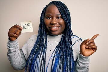 Young african american plus size woman with braids holding reminder paper with yes message very...