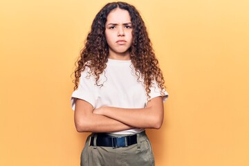 Beautiful kid girl with curly hair wearing casual clothes skeptic and nervous, disapproving expression on face with crossed arms. negative person.