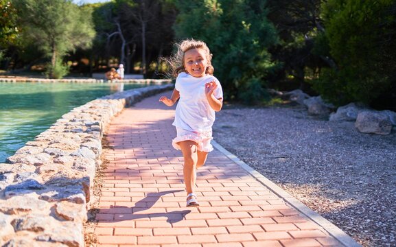 Adorable blonde child smiling happy. Running with smile on face around the park