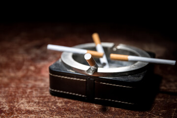 Ashtray and butts cigarettes on dark background. Selective focus