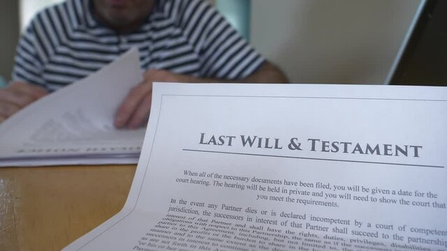 Man On The Background Reading And Reviewing The Details Of A Last Will And Testament Document.