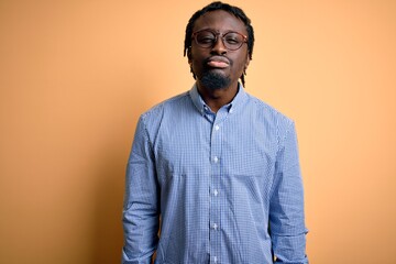 Obraz premium Young handsome african american man wearing shirt and glasses over yellow background looking at the camera blowing a kiss on air being lovely and sexy. Love expression.