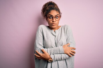 Young beautiful african american girl wearing sweater and glasses over pink background shaking and...