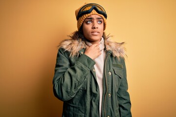 Young african american afro skier girl wearing snow sportswear and ski goggles Touching painful neck, sore throat for flu, clod and infection