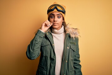 Young african american afro skier girl wearing snow sportswear and ski goggles mouth and lips shut...