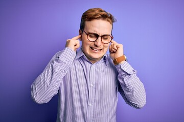 Young handsome redhead man wearing casual shirt and glasses over purple background covering ears with fingers with annoyed expression for the noise of loud music. Deaf concept.