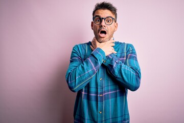Fototapeta premium Young handsome man wearing casual shirt and glasses standing over isolated pink background shouting and suffocate because painful strangle. Health problem. Asphyxiate and suicide concept.