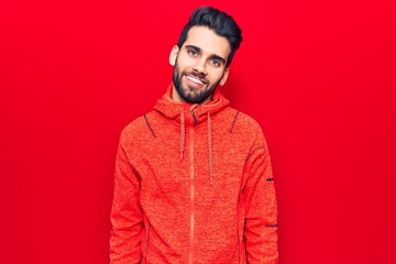 Young handsome man with beard wearing casual sweatshirt with a happy and cool smile on face. lucky person.