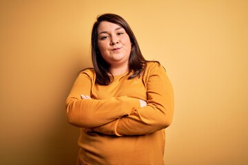 Fototapeta premium Beautiful brunette plus size woman wearing casual sweater over isolated yellow background skeptic and nervous, disapproving expression on face with crossed arms. Negative person.