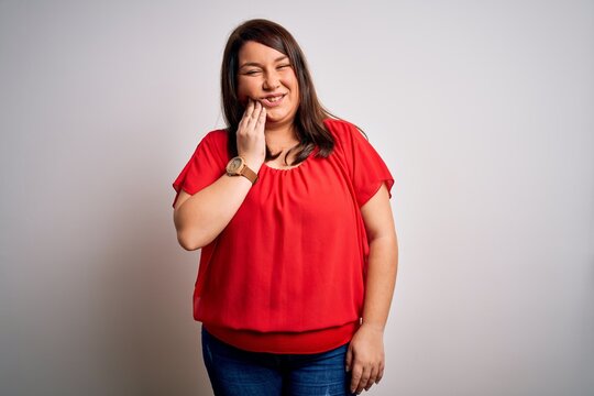 Beautiful brunette plus size woman wearing casual red t-shirt over isolated white background touching mouth with hand with painful expression because of toothache or dental illness on teeth. Dentist