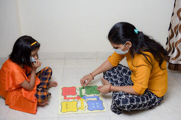 indian mom and daughter play indoor games with wearing mask  due to coronavirus