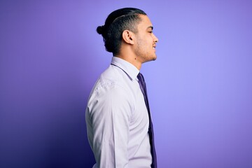 Obraz premium Young brazilian businessman wearing elegant tie standing over isolated purple background looking to side, relax profile pose with natural face and confident smile.