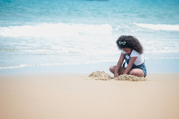 Cute kid girl having fun on sandy summer beach with blue sea, happy childhood friend making sand castle, playing with sandat on tropical beach