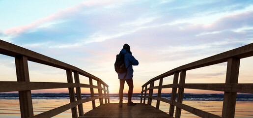 a man standing on a wooden bridge in the lake against the sunset evening.