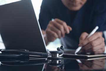 Doctor working on laptop computer and digital tablet for online medical or telemedicine concept