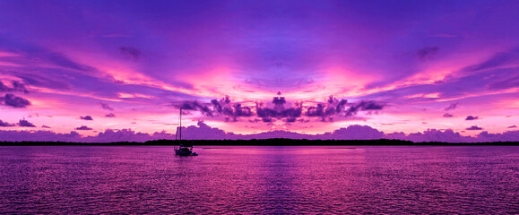 A bright  pink magenta coloured cloudy nautical coastal sunrise seascape in a purple sky....