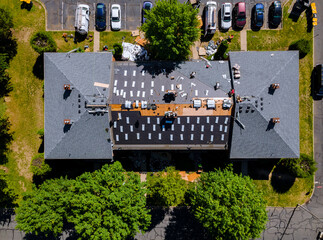 A roofer nailing shingles with air gun, replacing roof cover protection being applied © ungvar