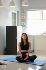Woman woman wearing exercise clothes work out at home, practicing yoga and sitting on yoga mat