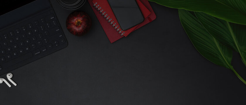 Digital tablet keyboard, smartphone above schedule books, copy space, apple and leaves decorated on black table